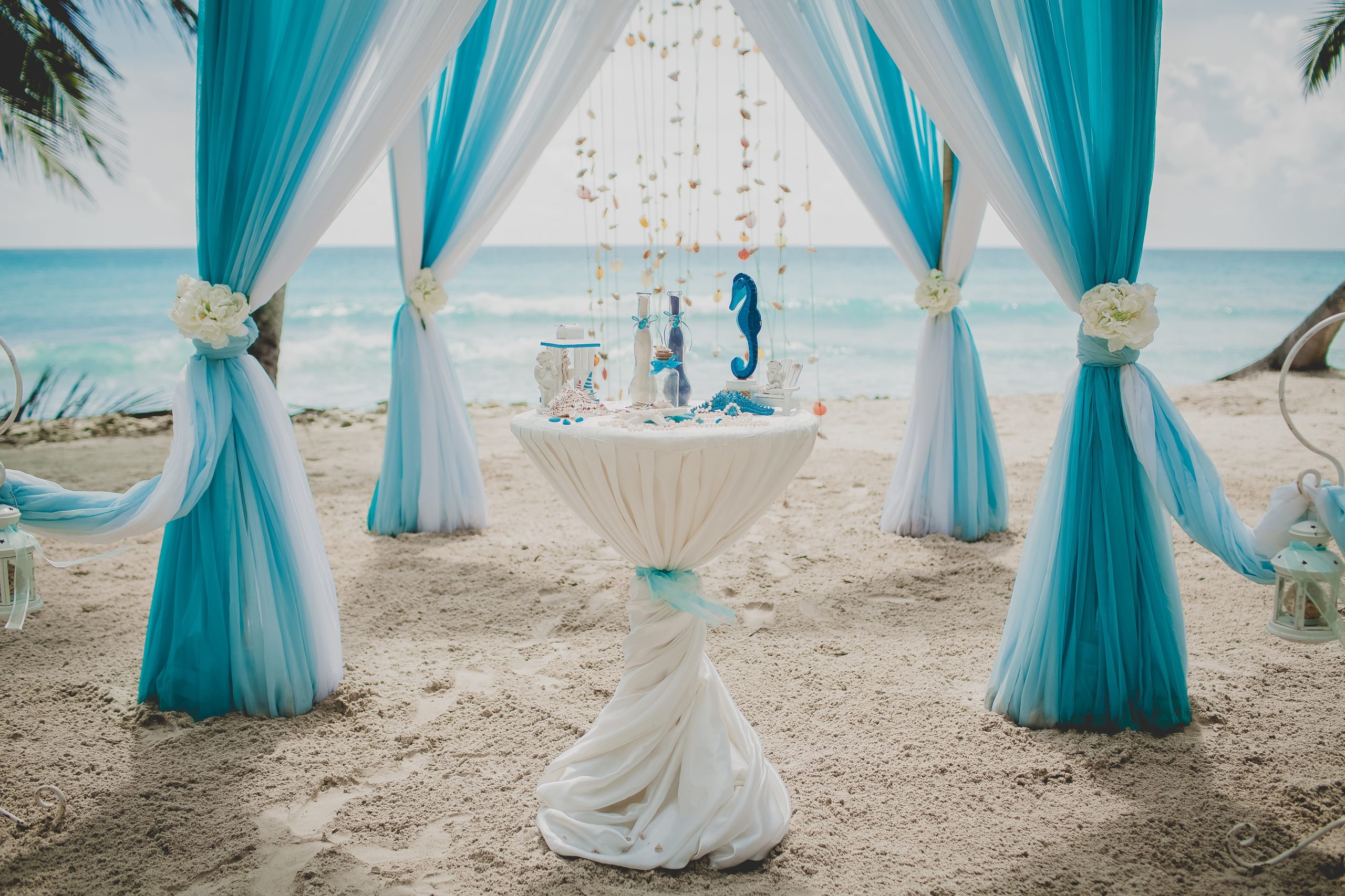 Blue and white wedding aisle in a beach surrounded by palms with the sea on the background