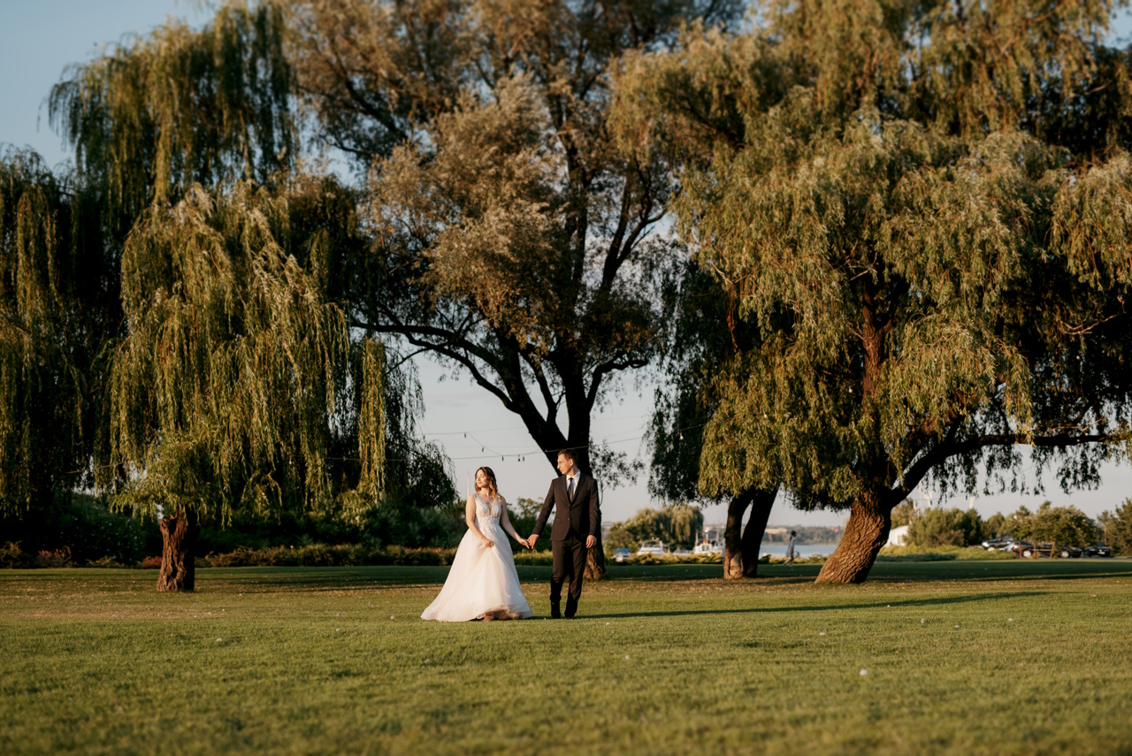 bride and groom walking in the park at sunset